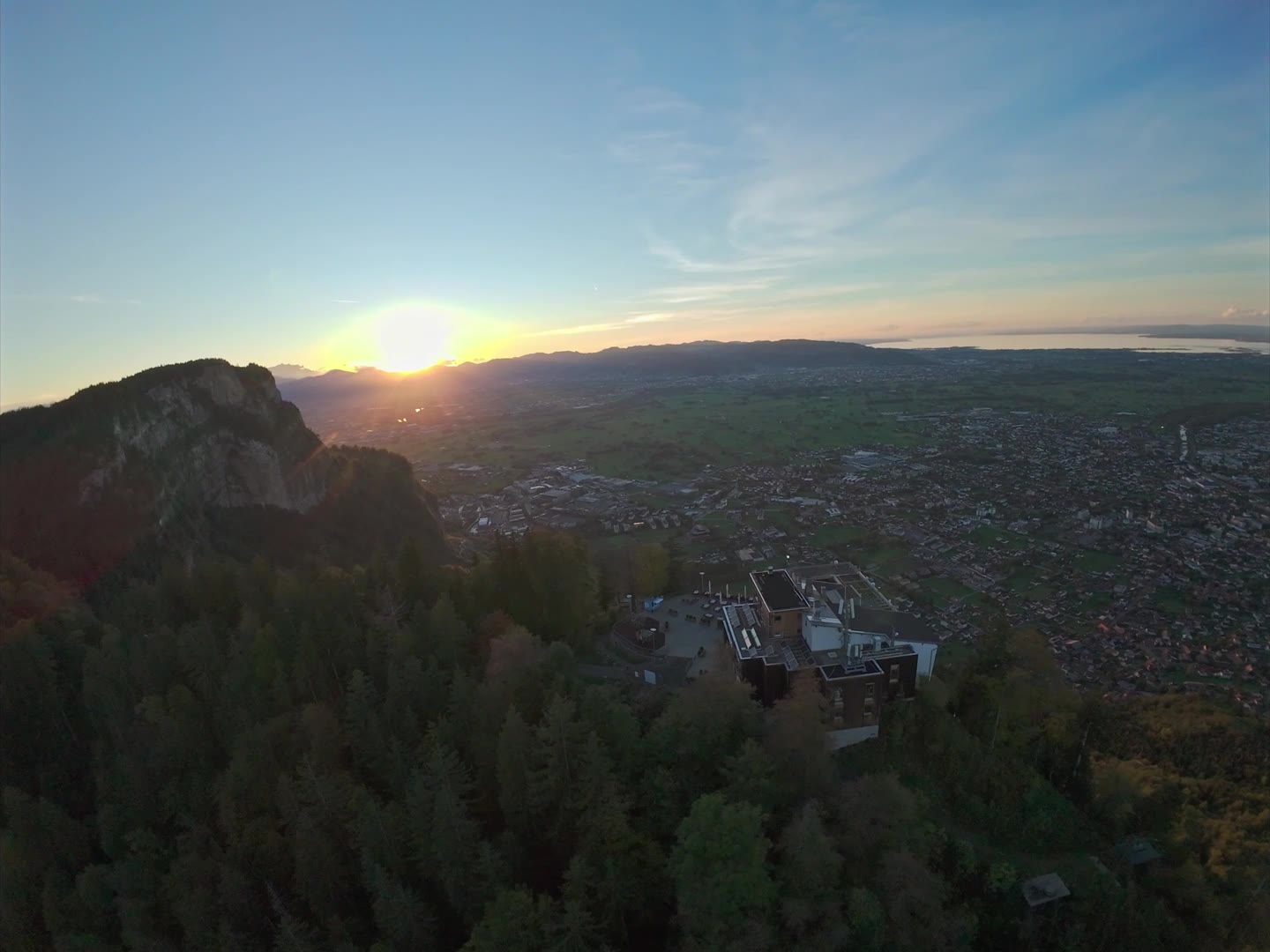 Sonnenuntergang hinter dem Karrenfelsen, darunter die Bergstation und Dornbirn im Rheintal